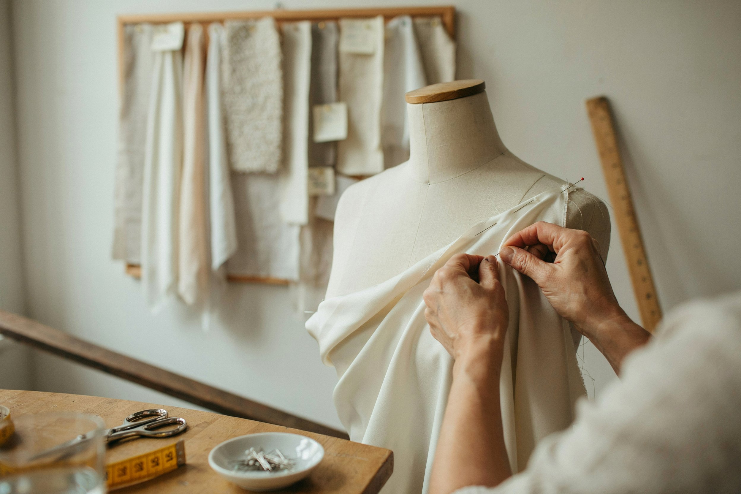 Tailor pinning fabric on a dress form during sample development
